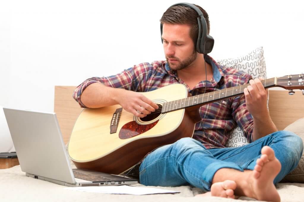 Musician playing guitar with computer