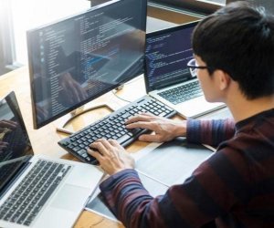 high schooler coding on three screens